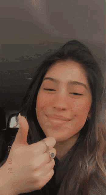 a woman is smiling and giving a thumbs up sign