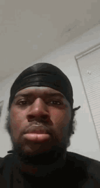 a man with a beard wearing a black headband is looking at the camera .