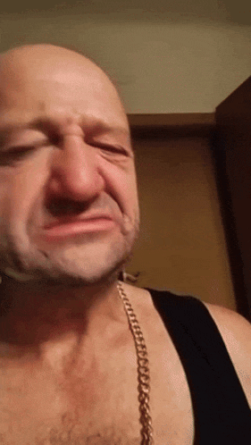 a man wearing a gold chain around his neck makes a funny face