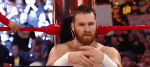 a man with a beard is sitting in a wrestling ring .