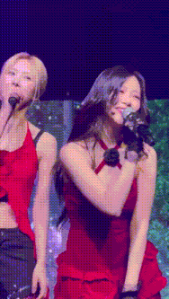 a woman in a red dress is singing into a microphone while standing next to another woman .