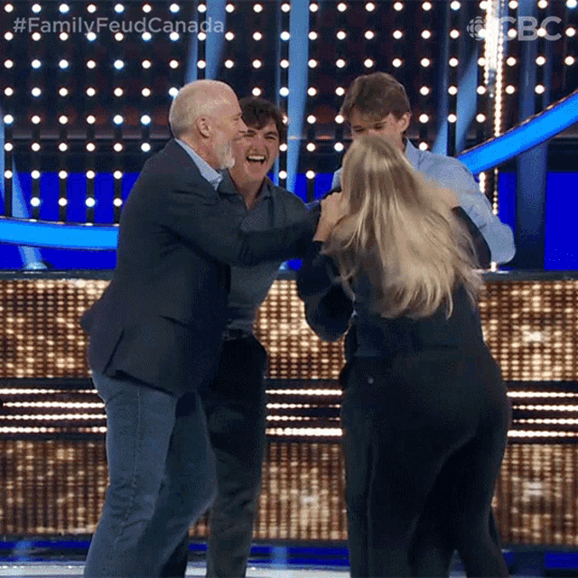 a group of people on a stage with the words family feud canada on the bottom left