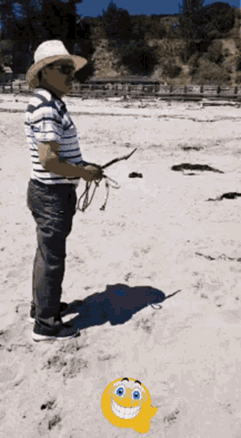 a man standing on a beach holding a fishing rod with a smiley face in the foreground