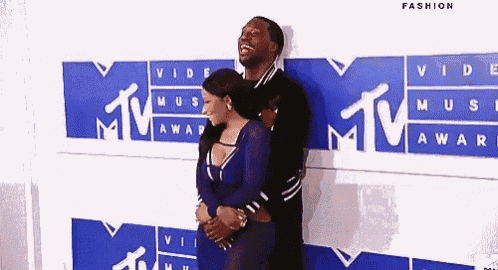 a man and a woman are standing next to each other on a blue carpet at awards .