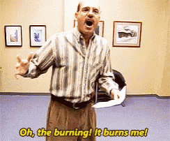 a man in a striped shirt is saying oh the burning it burns me while holding a piece of paper