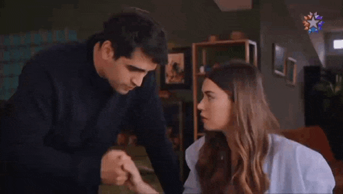 a man is kissing the hand of a woman while they are sitting at a table .