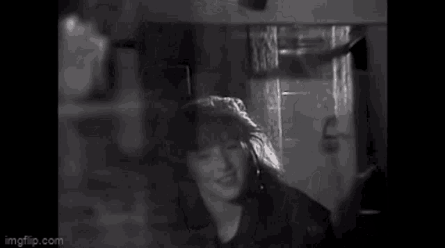 a black and white photo of a woman with long hair in a room .
