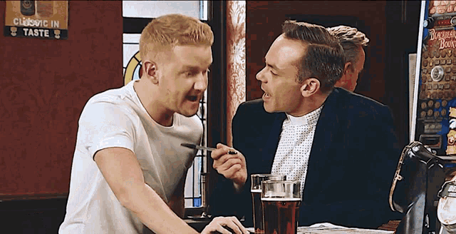 two men are sitting at a bar with a sign that says classic in taste