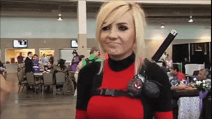 a woman in a deadpool costume holds a sword in her hand .