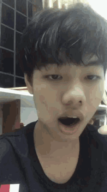 a young man is making a funny face with his mouth wide open .