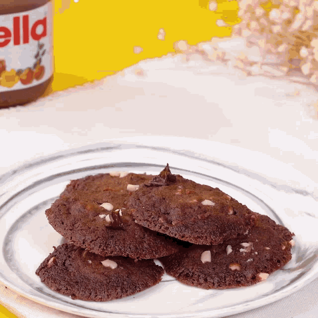a bottle of nutella sits behind a plate of chocolate cookies