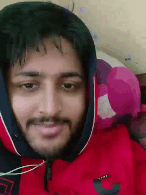 a man with a beard wearing a red hoodie and headphones