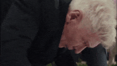 a man in a suit is laying on the ground with his head on his knees .