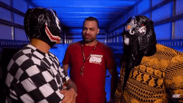 a man in a red shirt is talking to two men in masks in a truck .