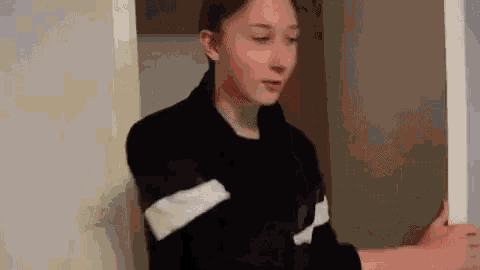 a young girl in a black jacket is standing in a doorway holding a picture frame .