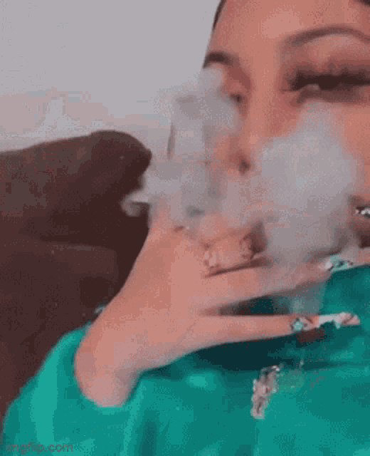 a woman is smoking a cigarette on a couch and blowing smoke out of her mouth .