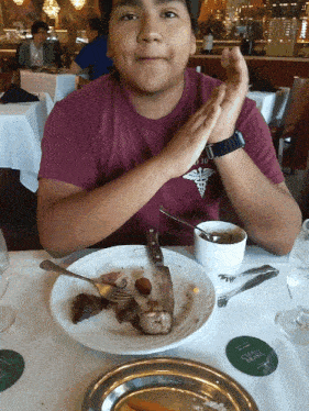 a boy sitting at a table with a plate of food and a coaster that says oak room