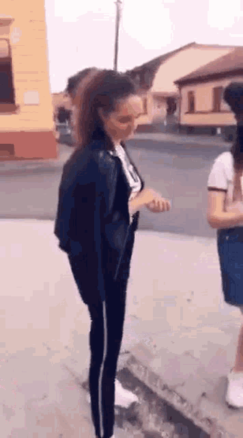 a woman is standing on the sidewalk next to a man .