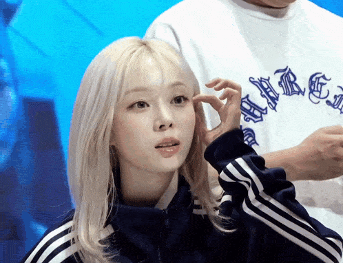 a woman with blonde hair is wearing a blue jacket with white stripes