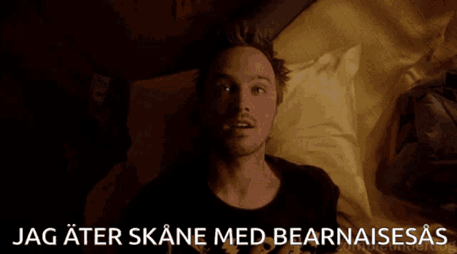 a man laying on a bed with the words jag ater skane med bearnaises written below him