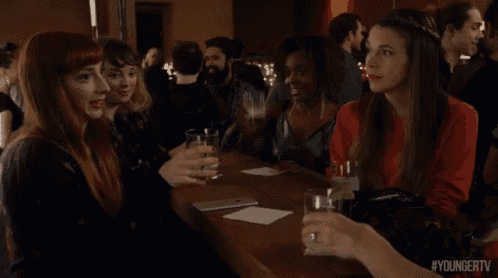 a group of people are sitting at a bar toasting with their glasses with the hashtag youngertv