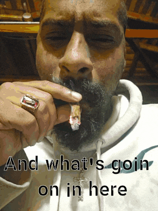 a man with a beard and a ring on his finger smoking a cigarette