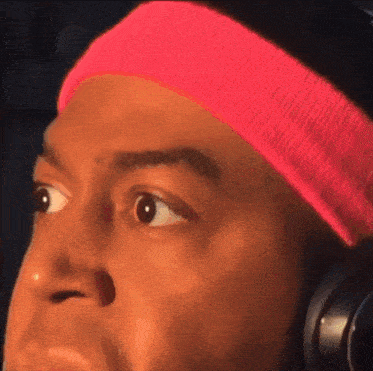 a man wearing a pink headband and headphones looks surprised