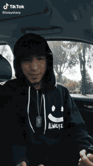 a man wearing a black hoodie with a smiley face on it