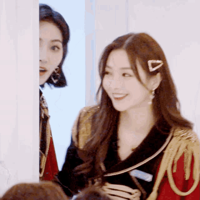 a woman with a hair clip in her hair is smiling while standing next to another woman