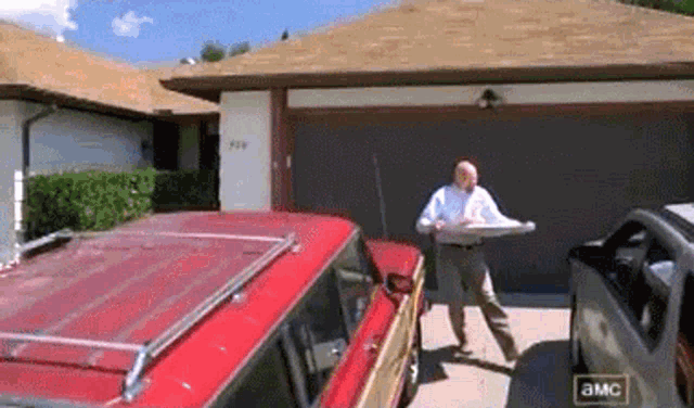 a man in a white shirt is standing in front of a red car that says a&mc on the side