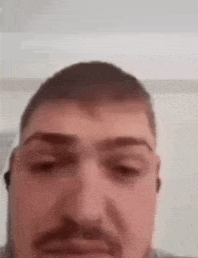 a man with a mustache is wearing headphones and looking at the camera .