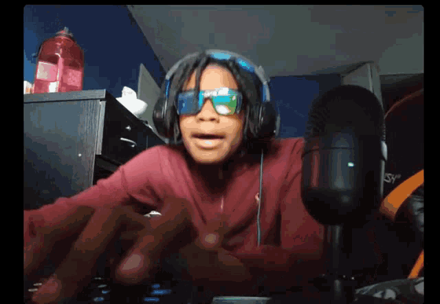a young boy wearing headphones and sunglasses is giving a peace sign