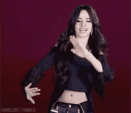 a woman is dancing in a crop top and jeans .