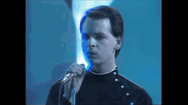 a man is singing into a microphone in front of a blue background .