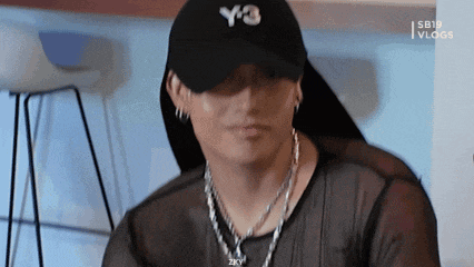 a close up of a person wearing a hat and necklace