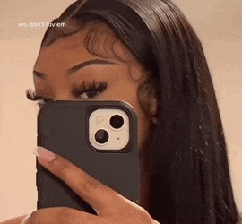 a woman is taking a picture of herself in a mirror with her phone .
