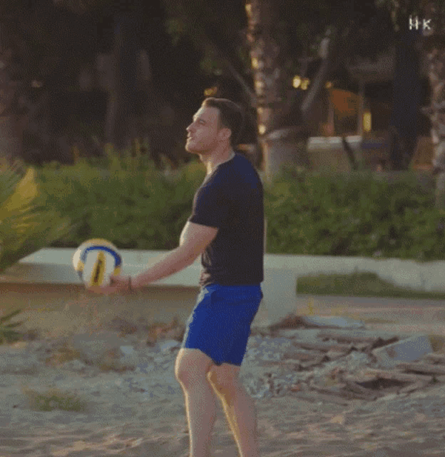 a man in a black shirt and blue shorts is throwing a ball