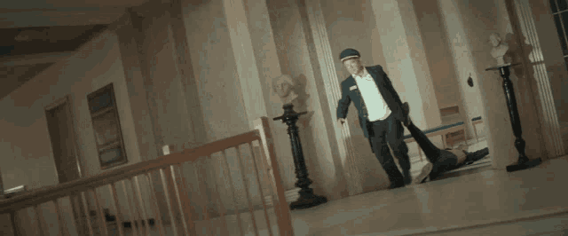 a man in a suit and hat is standing next to a man on the floor
