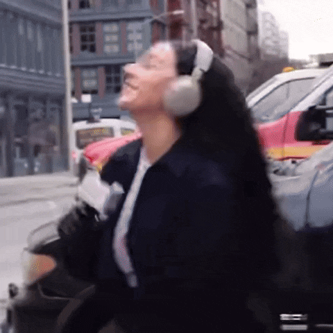 a woman wearing headphones is dancing on a city street