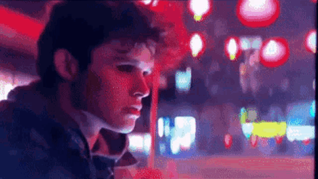 a man is looking at a computer screen with a blurry background of lights .