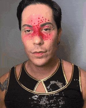 a man with red dots on his face is wearing a black and gold top