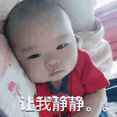 a baby in a red shirt is laying on a pillow with chinese writing on it