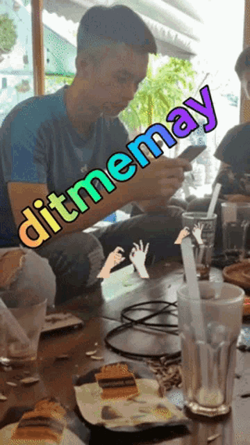 a man sits at a table with a sign that says ditmenmay on it