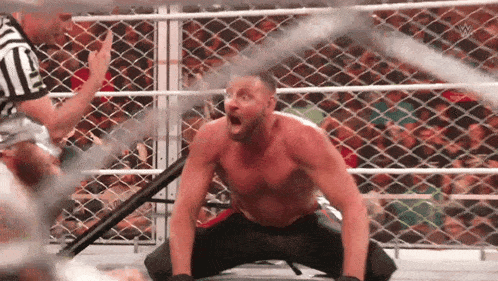 a shirtless wrestler is kneeling down in a ring with his mouth open