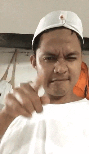 a man is wearing a white hat and making a funny face .