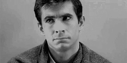a black and white photo of a man in a sweater making a funny face .