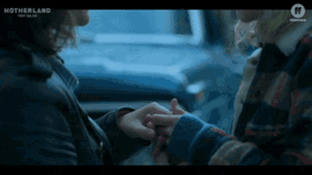 two people holding hands in a car with motherland written on the bottom