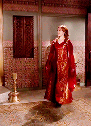a woman in a red dress stands in a room