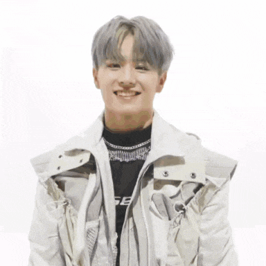 a young man wearing a black shirt and a white jacket is smiling