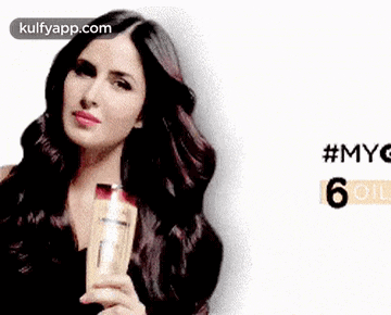 a woman with long dark hair is holding a bottle of shampoo .